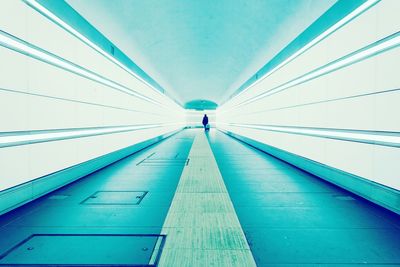 Silhouette walking in blue illuminated tunnel