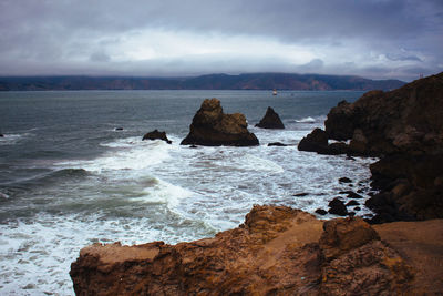 Rock formation in sea against sky