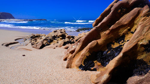 Rocks on beach against clear blue sky