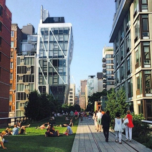 building exterior, architecture, built structure, city, men, person, city life, walking, lifestyles, large group of people, building, leisure activity, street, clear sky, modern, office building, skyscraper, tree, day