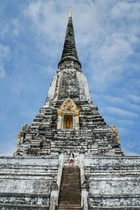 Low angle view of chedi phukhao thong against cloudy sky