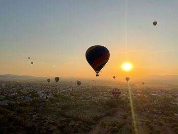 Hot air balloon flying over landscape against sky during sunset