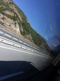 Road leading towards mountain seen through car window