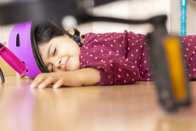 Girl wearing helmet with eyes closed fallen on floor