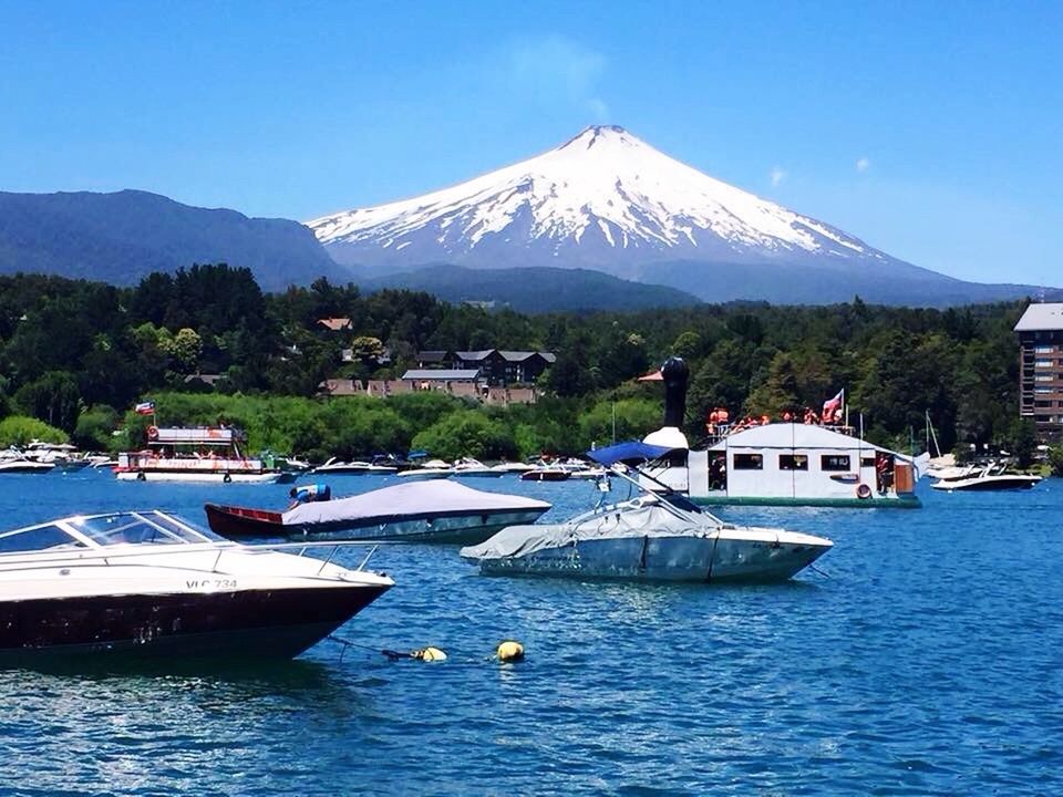 mountain, nautical vessel, transportation, tranquil scene, boat, scenics, mode of transport, mountain range, tranquility, blue, water, clear sky, tree, beauty in nature, waterfront, lake, mountain peak, nature, non-urban scene, tourism, travel destinations, calm, green color, physical geography, majestic, sky