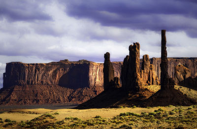 Rock formations on landscape against cloudy sky