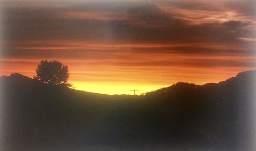 Scenic view of silhouette mountains against orange sky