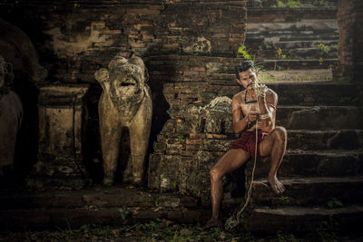 Full length of man tying rope on hand