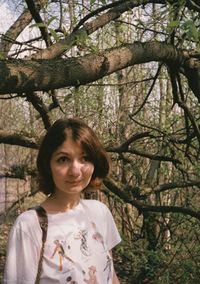 Portrait of young woman standing against trees