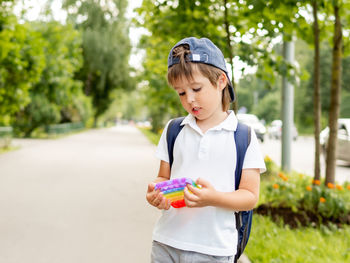 Little boy plays square rubber fidget toy pop it. rainbow-colored anti stress and tactile toy