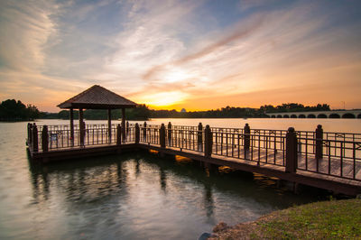 Jetty in lake against sky during sunset