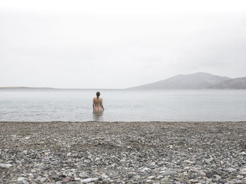 Rear view of man standing on sea against sky