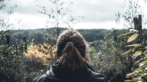 Rear view of woman looking at forest against sky