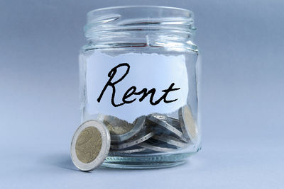 Close-up of coins in jar on table against blue background