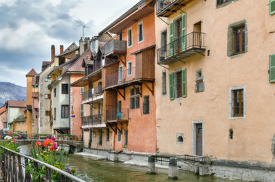 Residential buildings by canal against sky