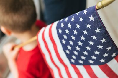 Rear view of boy holding american flag