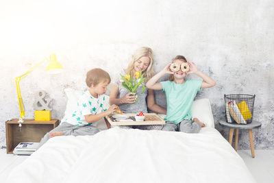 Mother with children having breakfast on bed