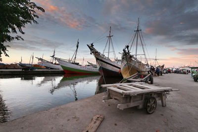 Boats moored at harbor against sky during sunset