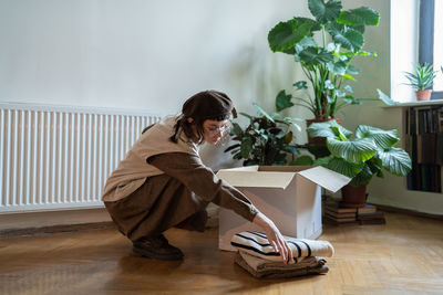 Girl activist, volunteer, altruist collecting things clothes for recycling put into cardboard box.