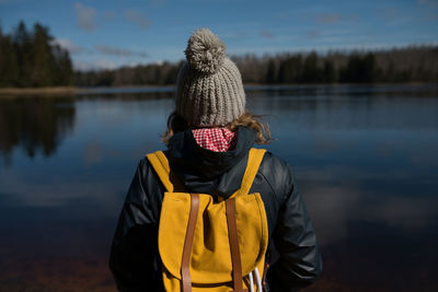Rear view of person standing by lake against sky