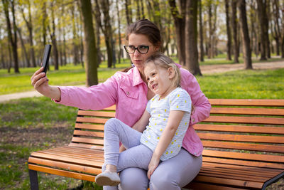 Souvenir photos of mother and daughter taken with a smartphone in a city park.