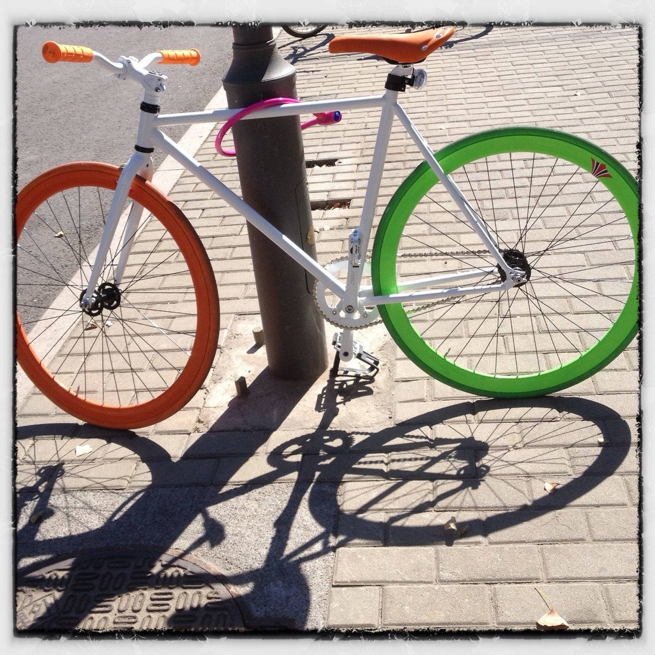 bicycle, transportation, mode of transport, transfer print, land vehicle, stationary, parked, parking, auto post production filter, wheel, street, day, shadow, cycling, sunlight, outdoors, cycle, travel, pole, built structure