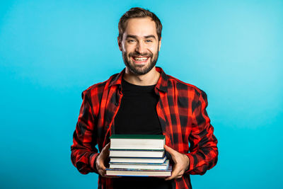 Portrait of smiling young man against blue background