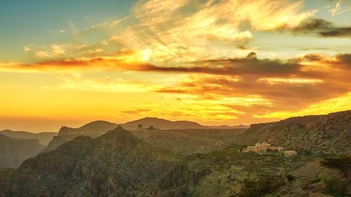 Scenic view of mountains against dramatic sky during sunset