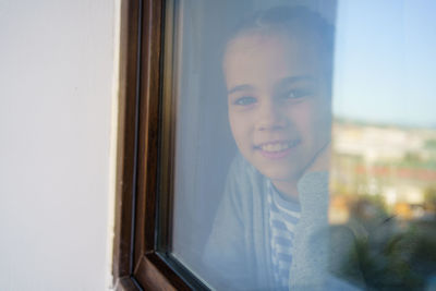 Portrait of smiling young woman seen through window