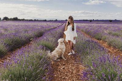 Woman with dog by purple flowering plants on land