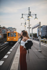 Side view of young woman standing on platform at railroad station