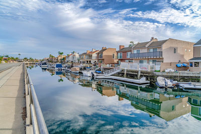 Buildings by canal against sky in city