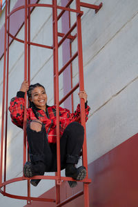 Smiling girl with african braids on a red metal ladder