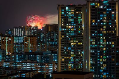 Illuminated modern buildings against sky at night