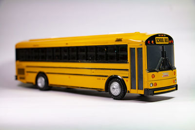 Close-up of yellow car on road against white background