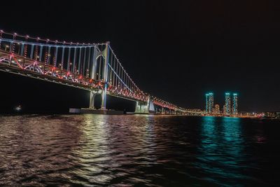 Illuminated suspension bridge over river at night