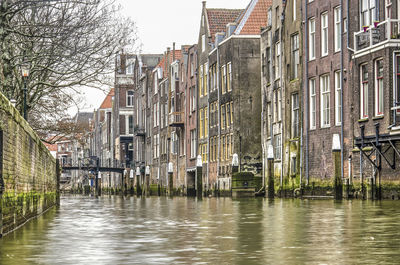 Buildings by river in city against sky