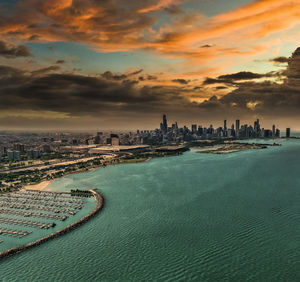 City by sea against sky during sunset