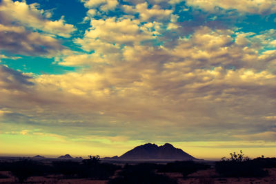 Scenic view of dramatic sky over silhouette landscape during sunset