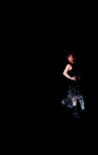 Side view of a young woman jumping over black background