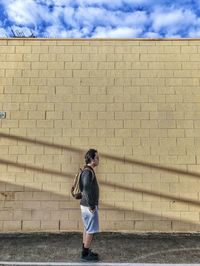 Full length of man standing against wall with shadows.