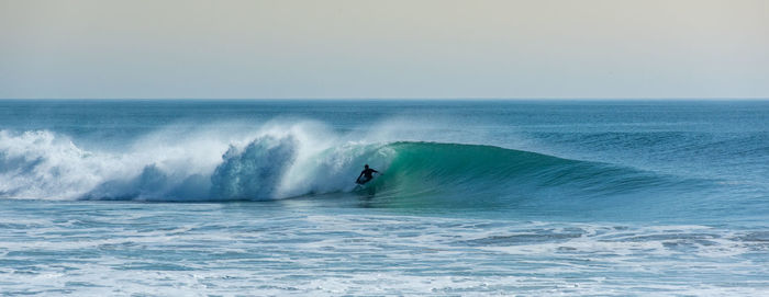 Panoramic view of person surfing in sea against clear sky