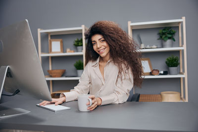 Portrait of smiling woman using laptop on table