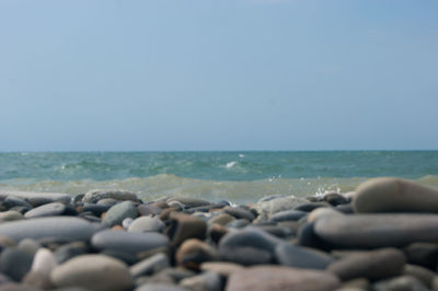 Pebbles on beach against clear sky