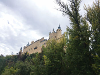 Low angle view of trees and building against sky