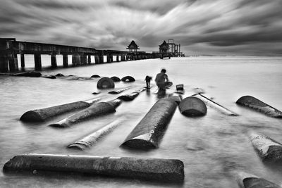 Pier on sea against cloudy sky