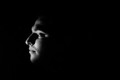 Close-up of thoughtful man against black background