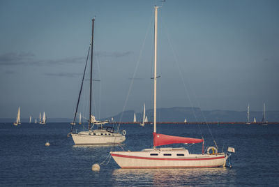 Sailboats moored on sea against sky