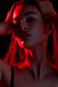 Close-up portrait of beautiful young woman against black background