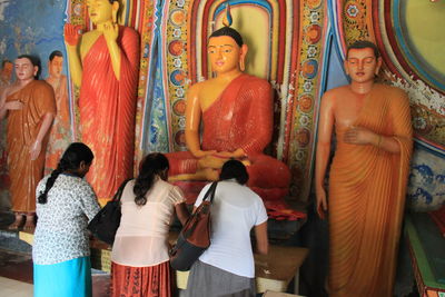 Women praying in front of buddha statues at temple